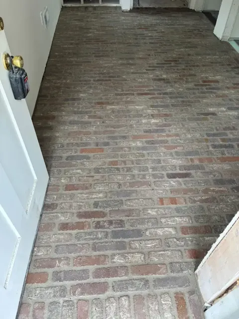 Hallway floor of thin red and grey brick laid in a running pattern
