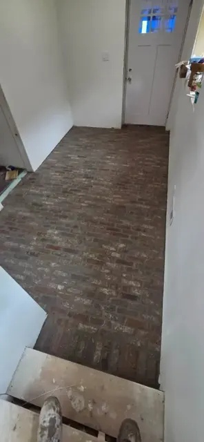 Narrow hallway with a new thin-brick floor, the doorway end not yet finished